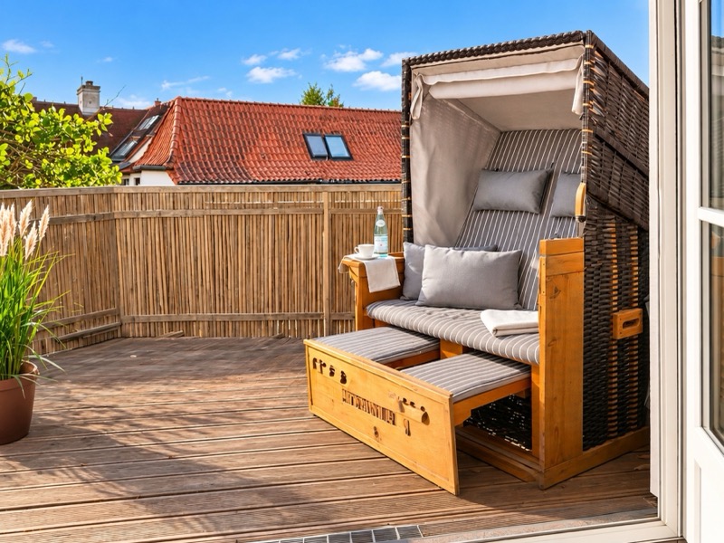 Sonniger Balkon mit Strandkorb und Holzterrasse