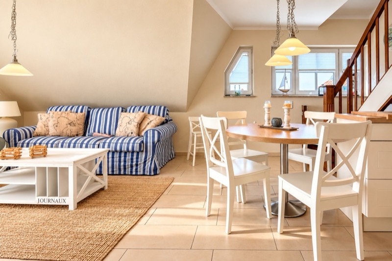 Wohn- und Essbereich mit gestreiftem Sofa und Treppe zur Galerie