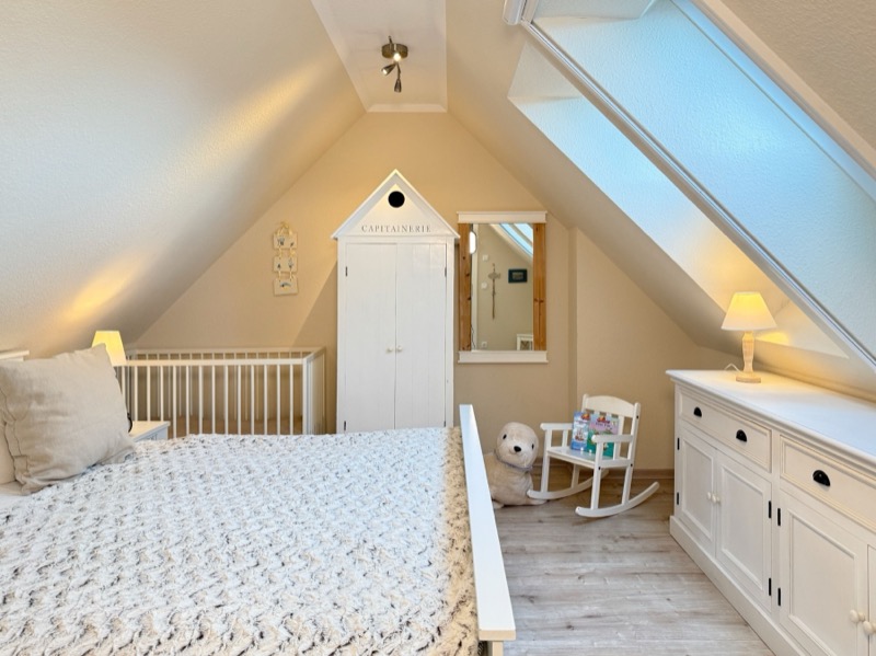 Schlafzimmer mit Doppelbett, Kinderbett und Dachfenster
